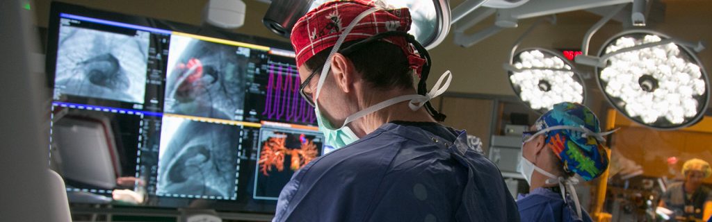 surgeon in front of a bank of monitors