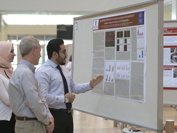 Scott Hagen, MD, (center) listens as Samer Abdul Kareem, MD, and Rand Al-Subu, MD, research assistants in the lab of Pelin Cengiz, MD, describe their research poster.