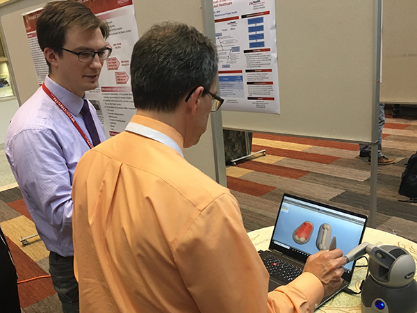 Brandon Tomlin, MD, watches as Jonathan Fliegel, MD, tries his hand at a virtual-reality–based neonatal intubation simulator