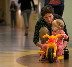 Dr. Carol Diamond playing with a child on a tricycle