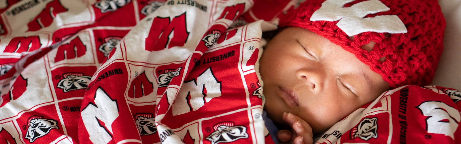 young baby wrapped in Wisconsin Badger blanket and hat