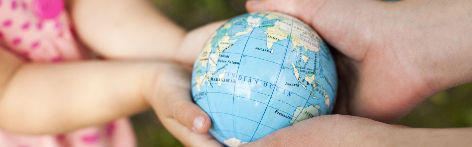 hands of a child and adult hold a tiny globe