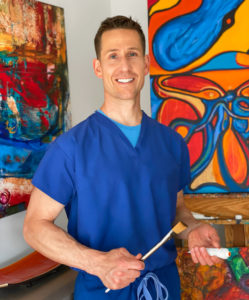 doctor holding paintbrush in front of paintings
