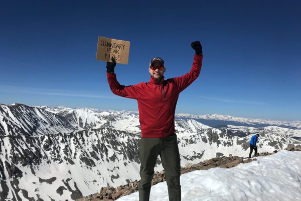 person holding a sign atop a mountain