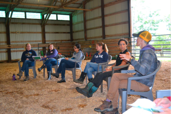 group of people sitting in a row in a barn