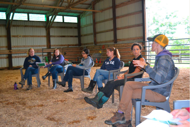 group of people sitting in a row in a barn