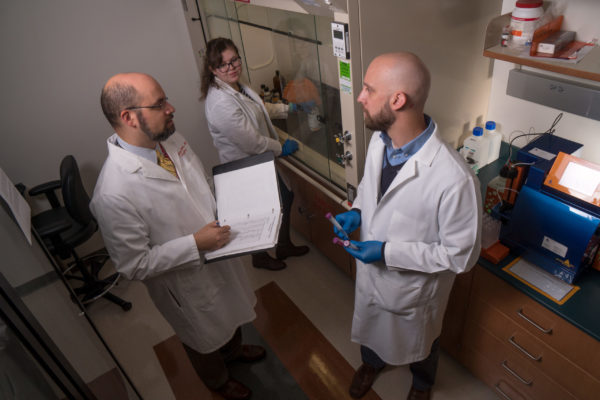 three scientists talking with one another