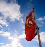 Puffy clouds and sunlight fill the sky as a W crest banner flutters in the wind