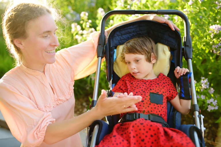 Woman,With,Disabled,Girl,In,A,Wheelchair,Walking,In,The