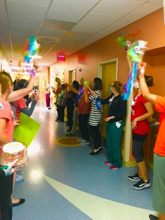 doctors and nurses celebrating a patient's successful treatment in a hospital hallway
