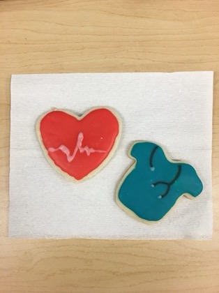 a red cookie shaped like a heart and a blue cookie shaped like scrubs