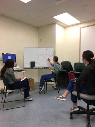 two residents watching while another writes on a dry erase board