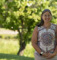 Laura Houser standing outside with a green field behind her