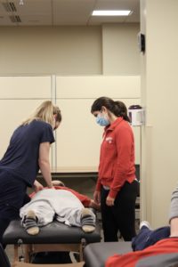 a man is lying on his stomach while a woman manipulates his back, another woman watches