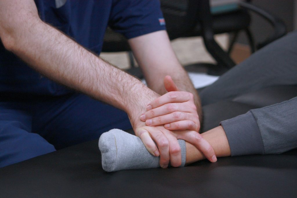 a pair of hands manipulating another person's ankle