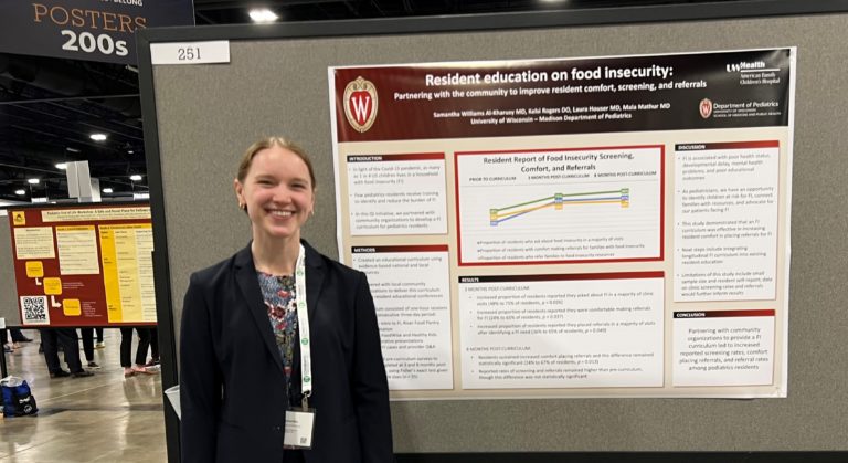 a smiling woman standing in front of a poster she is presenting. The poster is titled "Resident Education on Food Insecurity"