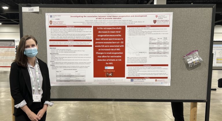 a woman wearing a mask standing in front of a poster she is presenting. The poster is titled "Investigating the association between renal tissue oxygenation and development of AKI in preterm neonates"