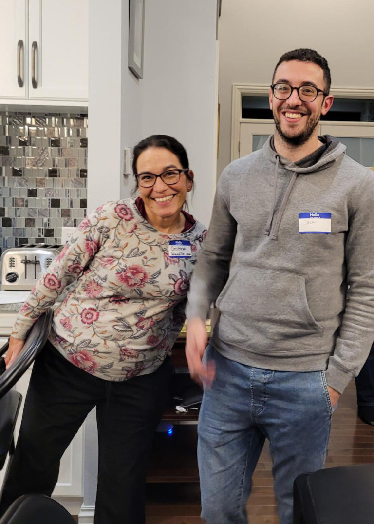 two people standing in a kitchen smiling at the camera