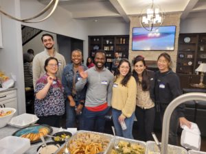 group of people smiling at the camera and standing in a kitchen in front of a buffet of food