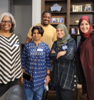 group of people standing in a dinning room smiling a camera