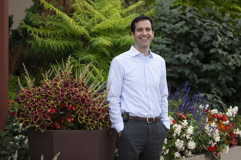 Ryan Coller standing in front of a outdoor flower garden