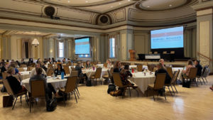 crowd of conference-goes sitting at round tables in a large open room