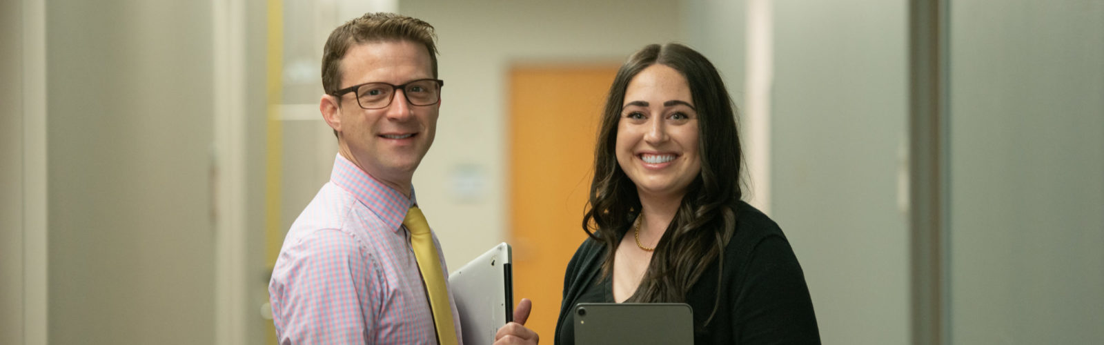 2 Department of Pediatrics staff holding devices in a hallway.