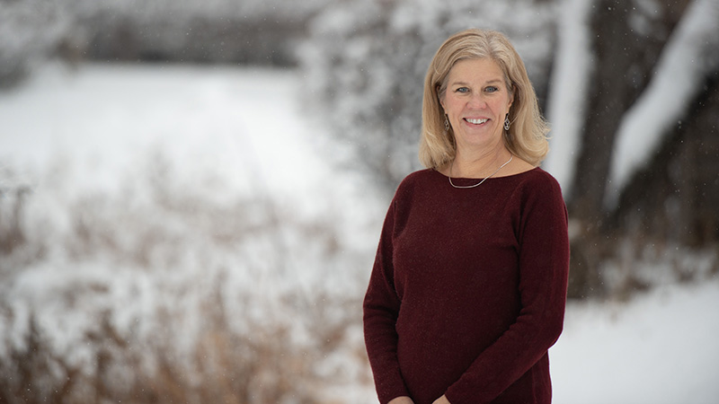 Dr. Amy Plumb wearing a burgundy sweater and standing outside as snow falls