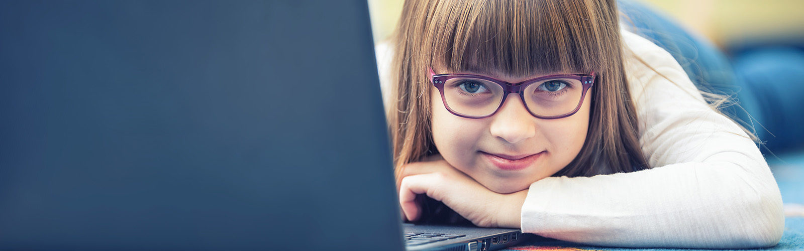 pre-teen wearing purple glasses on floor with laptop computer