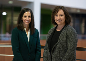 Katie Denzin and Kristin Determan standing in an atrium and smiling at the camera