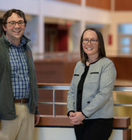 Doug Dean and Catherine Allen standing in an atrium looking at the camera and smiling