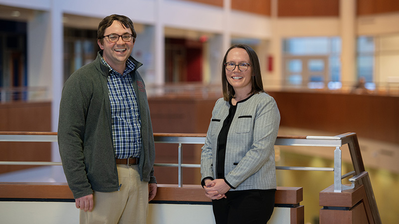 Doug Dean and Catherine Allen standing in an atrium looking at the camera and smiling