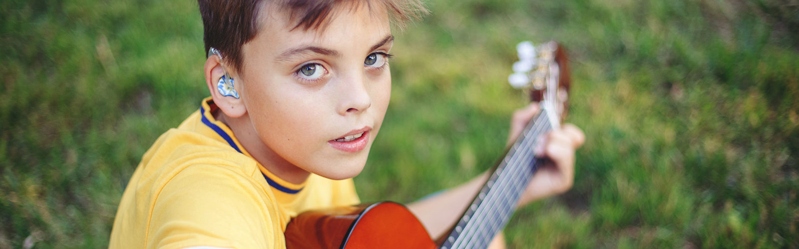 young adolescent playing guitar outside