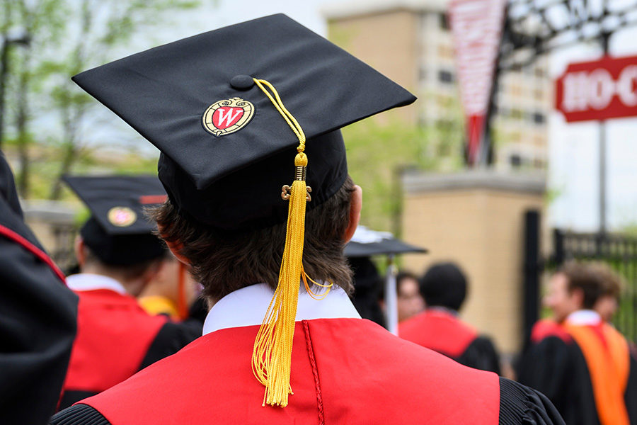 student wearing a black graduation cap with a yellow tassel at the University of Wisconsin crest