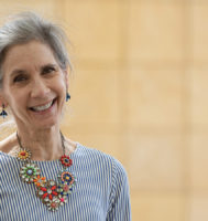 Woman smiling at the camera wearing a striped shirt and a colorful flower necklace