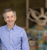 Man wearing blue Oxford shirt standing in front of a colorful Bucky Badger statue in the background