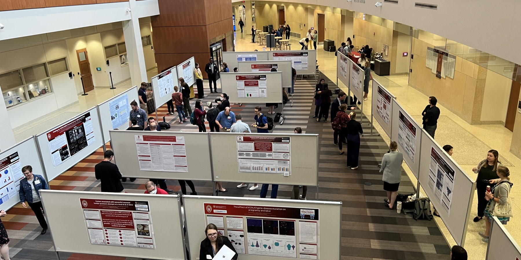 an indoor atrium full of people looking at poster boards