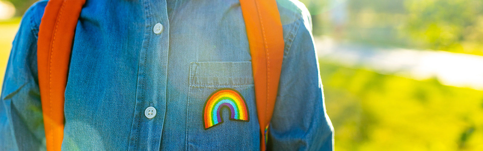 child wearing denim shirt with a rainbow patch on the pocket