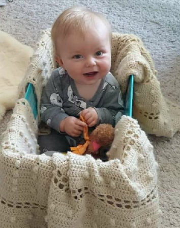 a smiling baby sitting upright in a crib