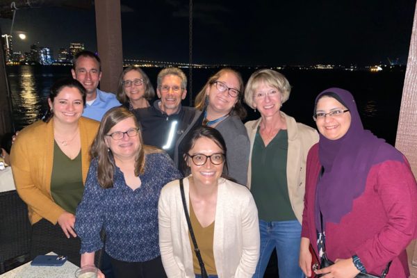 a group of smiling men and women seated by the lake at night