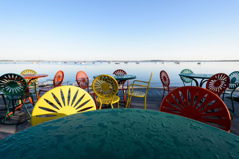 colorful tables and chairs against a lake background