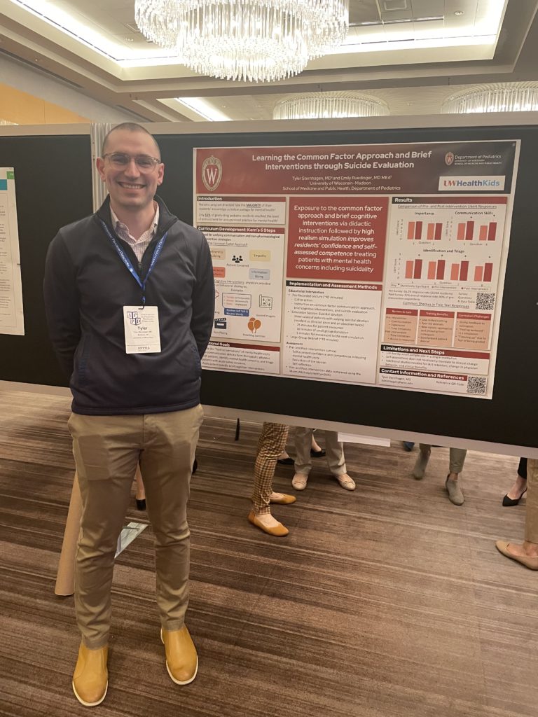 a smiling man standing next to a research poster