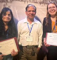 Two people holding award certificates with a third person in the middle