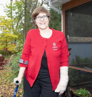 woman standing outside wearing a red cardigan and smiling at the camera