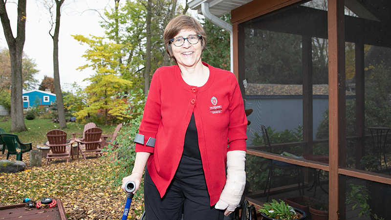 woman standing outside wearing a red cardigan and smiling at the camera