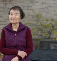woman wearing purple shirt and vest standing outside