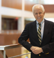 Dr. Norman Fost leaning against a railing and smiling at the camera
