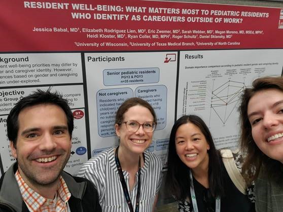 Group of four people standing in front of a scientific poster.