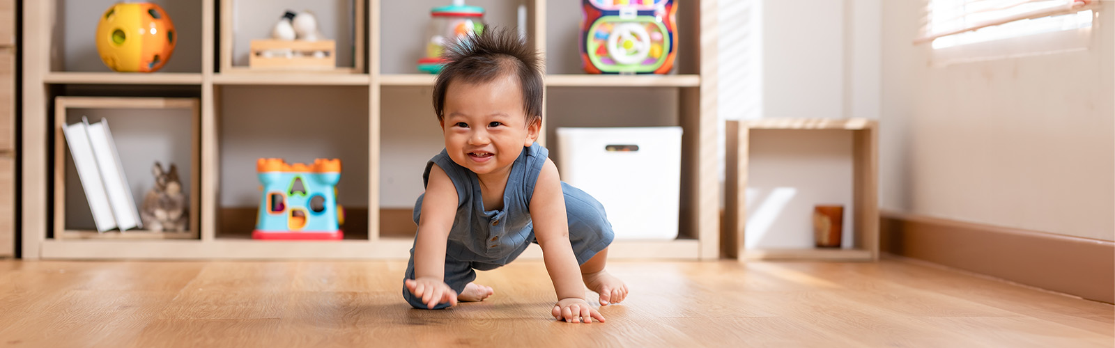 toddler crawling across a wooden floor in a play room