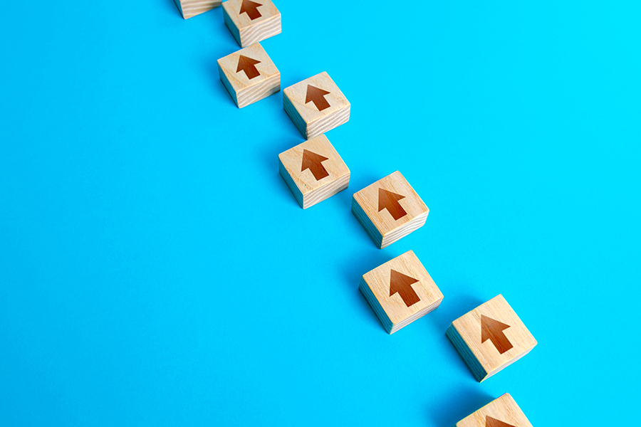 line of wooden blocks with arrows pointing up against a blue background